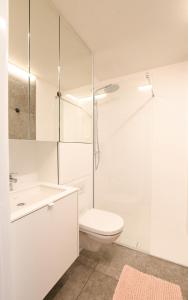 a white bathroom with a toilet and a sink at Studio zwembad met frontaal zeezicht in Ostend