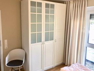 un armario blanco en un dormitorio con silla en Ferienwohnung Möwennest N°3, en Grömitz