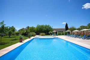 a swimming pool with chairs and a house at Agroturisme Na Martina in Portopetro