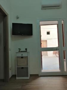 Pokój z przesuwnymi szklanymi drzwiami i telewizorem w obiekcie Casa per Vacanze a Marsala w mieście Marsala