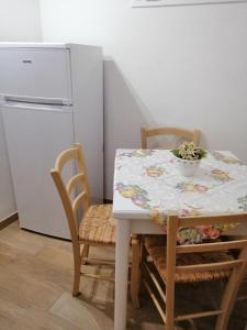 a table and chairs with a table and a refrigerator at Casa per Vacanze a Marsala in Marsala