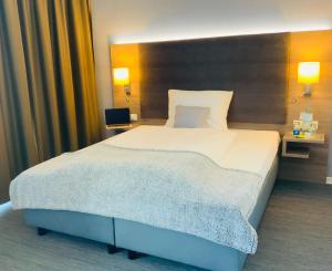 a large bed in a hotel room with two lamps at StadtHotel ARTE in Remagen