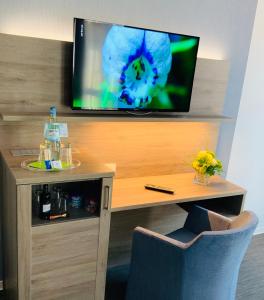 a room with a tv on a wall with a table and a desk with at StadtHotel ARTE in Remagen