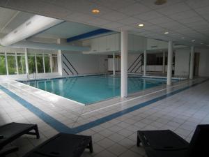 a large swimming pool with blue water in a building at Hollumerduinen in Hollum