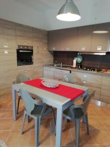 una cocina con mesa y sillas, mesa roja y sillón en Casa di Gabry, en Torino di Sangro