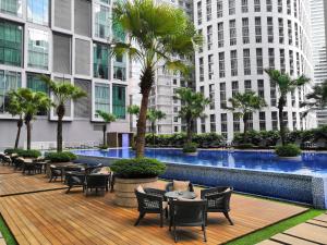 una piscina con mesas, sillas y edificios en Soho Suites KLCC by Airhost en Kuala Lumpur