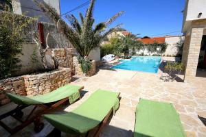a patio with two chairs and a swimming pool at Apartman Murter Chill Spot A2+1 ID 722 in Murter