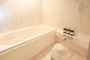 a white bathroom with a tub and a toilet at Kanazawa Bettei Yuan in Kanazawa +47 photos