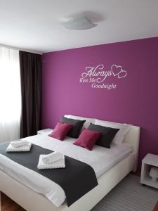 ein Schlafzimmer mit einem großen Bett mit einer lila Wand in der Unterkunft Apartman Kristian in Velika Gorica