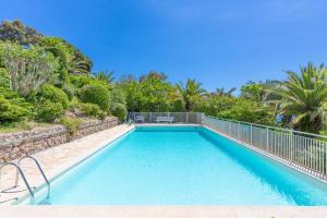 a swimming pool with a fence and trees at Appartement vacances cannes in Cannes