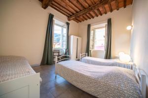 a bedroom with two beds and two windows at Ostello Palazzo Nizza in Massa