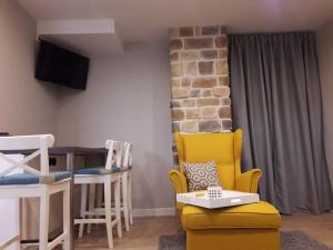 a living room with a yellow chair and a table at Alpine Cottage in Bled