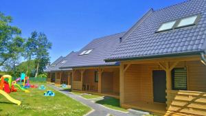 une maison en bois avec une aire de jeux dans la cour dans l'établissement Nadmorski Skarb Domki Apartamentowe, à Ostrowo