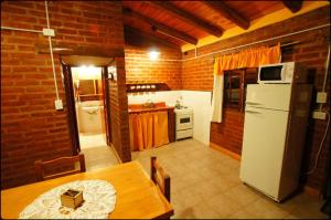 a kitchen with a table and a white refrigerator at Complejo de Cabañas Tierra Nuestra in Mina Clavero