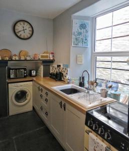 a kitchen with a sink and a clock on the wall at 2 Emma Place in Bodmin