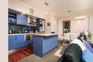 a large kitchen with blue cabinets and a couch at Wilkes Way Villa in Picton