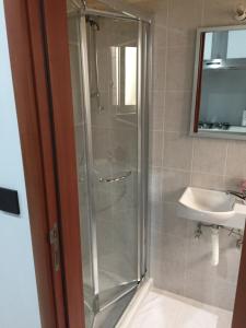 una doccia con porta in vetro accanto a un lavandino di 27A a Marsalforn
