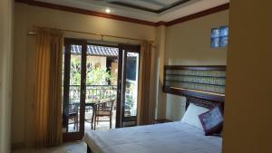 ein Schlafzimmer mit einem Bett und ein Balkon mit einem Tisch in der Unterkunft Kabera Bungalow 3 in Ubud