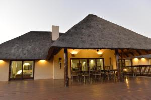 a building with a thatched roof with tables and chairs at Wildlife Estate House With Mountain Views & 12-Meter Pool in Hoedspruit