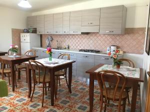 a kitchen with wooden tables and chairs and white cabinets at S'Apprigu B&B in Càbras