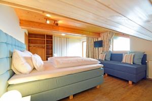 een slaapkamer met een bed en een blauwe bank bij Pleschinhof in Velden am Wörthersee