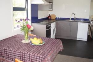 a kitchen with a table with a plate of fruit on it at Waihakeke Cottage in Carterton
