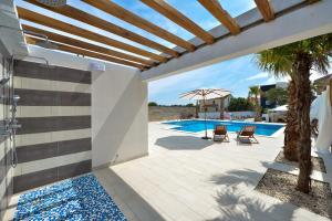 a patio with a pool and a palm tree at Boutique Residence Cosmopolis 1 in Bibinje