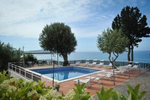 皮肖塔Residence Punta Cilento的一个带椅子和树木的游泳池以及大海