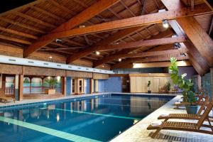 an indoor swimming pool with wooden ceilings and a large house at Hotel & Résidence Les Vallées Labellemontagne in La Bresse