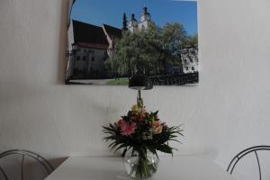 a vase of flowers on a table with a picture on the wall at Gästewohnung Müntzer in Lutherstadt Wittenberg