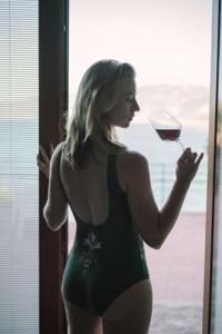 une femme en bikini tenant un verre de vin dans l'établissement Blue Bay, à Cefalù
