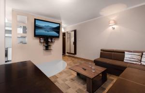 a living room with a couch and a tv on a wall at Apartament Deluxe Arcon in Siemianowice Śląskie