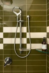 a shower head in a green and white tiled bathroom at Wilkes Way Villa in Picton