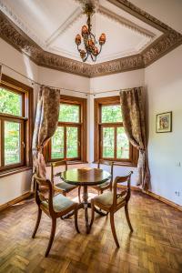 a dining room with a table and chairs and windows at Villa Apartments by the sea in Liepāja