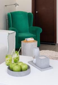 a living room with a green chair and apples on a table at Eva Mare Hotel & Suites - Adults only in Agia Pelagia