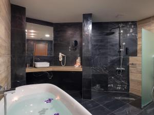 a bathroom with a bath tub and a shower at Eva Mare Hotel & Suites - Adults only in Agia Pelagia