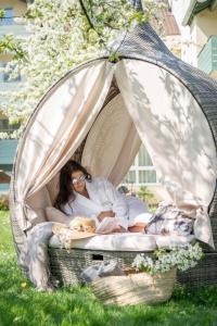 a woman laying on a bed in a tent with a dog at Fichtenwald-Ihr Boutique I Glück`s Hotel - Ihr Kraftort - Wasserwelten Bad Füssing in Bad Füssing