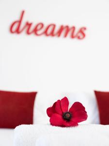 a red flower on top of a bed with the word dreams at Eva Mare Hotel & Suites - Adults only in Agia Pelagia