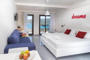 a living room with two white beds and a blue couch at Eva Mare Hotel & Suites - Adults only in Agia Pelagia
