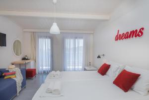 a bedroom with a large white bed with red pillows at Eva Mare Hotel & Suites - Adults only in Agia Pelagia