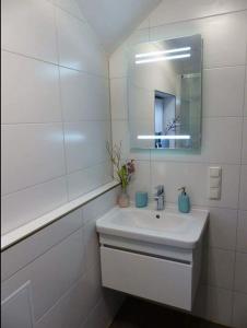 a white bathroom with a sink and a mirror at Darßer Strandgut - Haus Butzek in Ahrenshoop