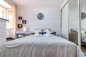 1 dormitorio blanco con 1 cama grande y espejo en Beau studio à 50m de la plage, en Niza