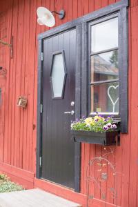 una puerta negra con una ventana y flores en una caja de la ventana en Sörtorpets gårdshus, en Älvkarleby