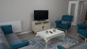 a living room with a tv and two chairs and a coffee table at Fursan Apart My Doğa in Trabzon