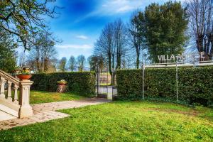 une porte menant à un jardin avec un panneau sur une haie dans l'établissement Villa Agnese Suites, à Lucques