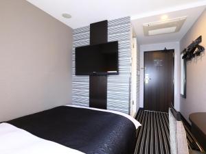a bedroom with a large bed and a television at APA Hotel Shimbashi Toranomon in Tokyo