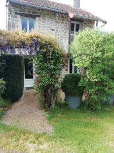 una casa con flores púrpuras delante de ella en Gîte du mont de transet en Thauron