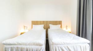 two beds in a hotel room with white sheets at Horeum Boutique Hotel in Sibiu