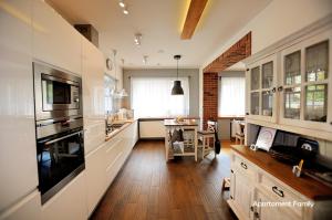 uma cozinha com armários brancos e piso em madeira em Biały Dom - 2 Bedrooms em Katowice