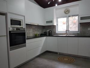 a kitchen with white cabinets and a clock on the window at Join our relaxed house near the beach - Mosteiros in Mosteiros